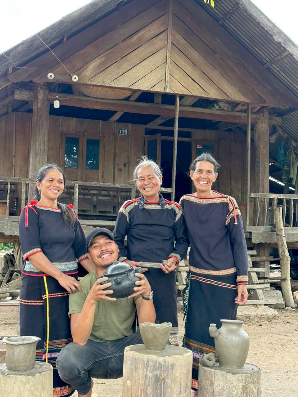 M'nong hosts and a guest in front of a traditional house
